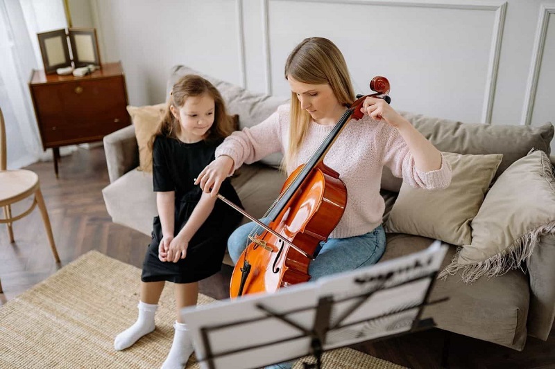 A lady is teaching voiline to the small girl
