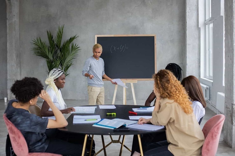 A tutor is teaching something in the blackboard.