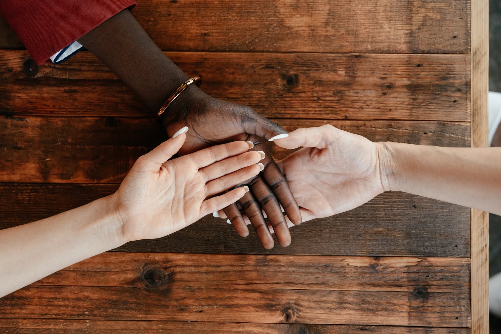 Three people touch hands in the middle of a table