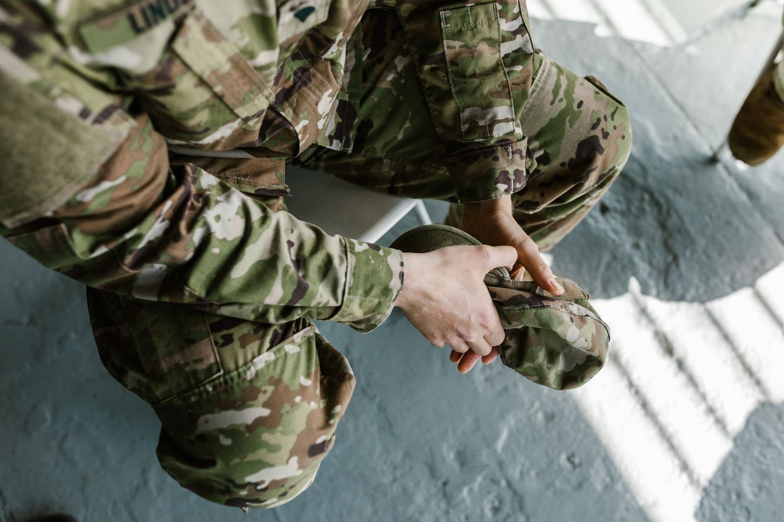 A member of the military service sitting down, clutching their cap in their hands.