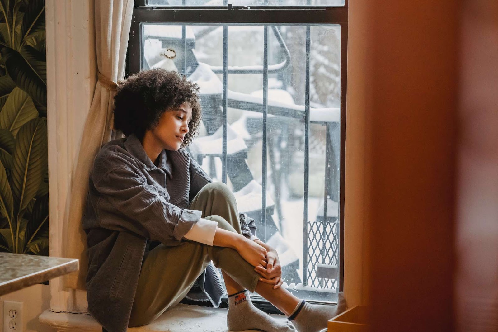 Sad woman sitting in windowsill