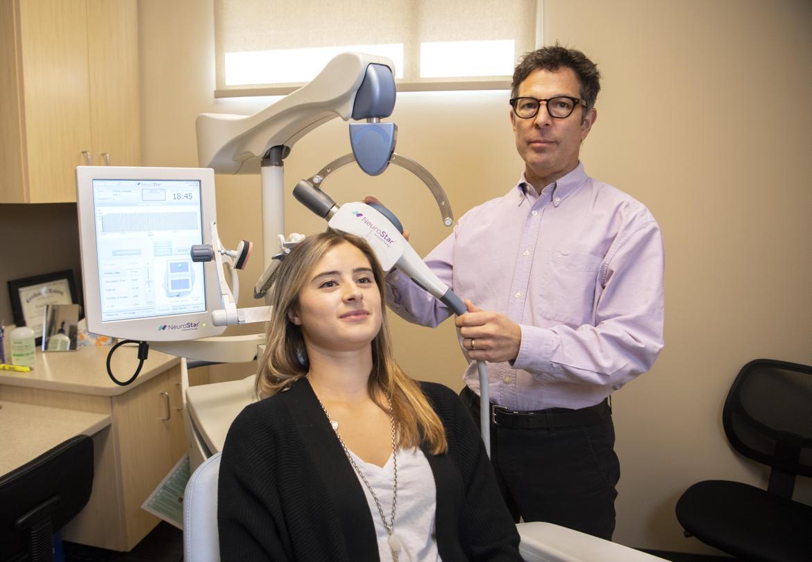Technician applies TMS to patient's head uses the electromagnetic coil