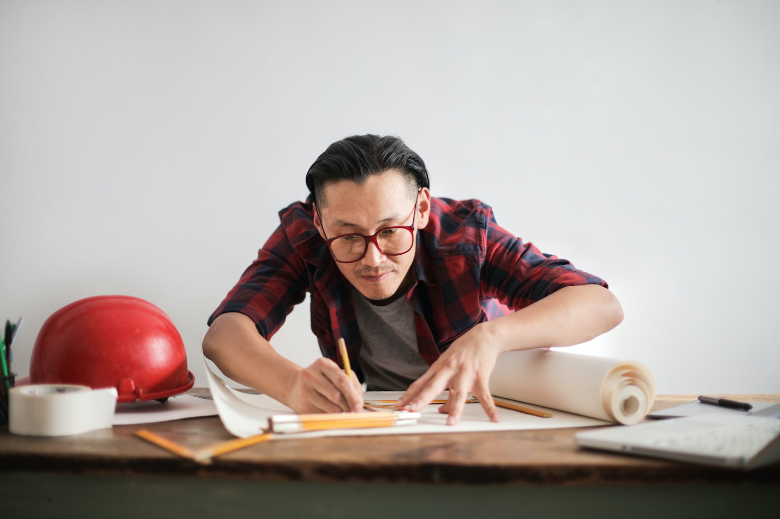 a man in a red flannel shirt who grew up as a gifted child completing blueprints for work
