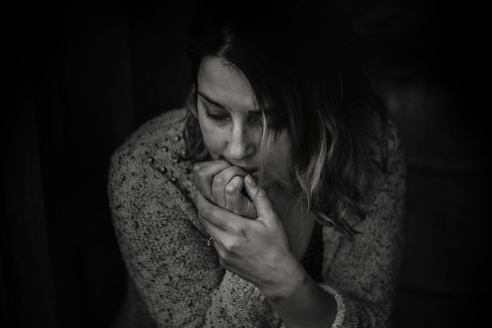 A woman curled up and biting her nails.