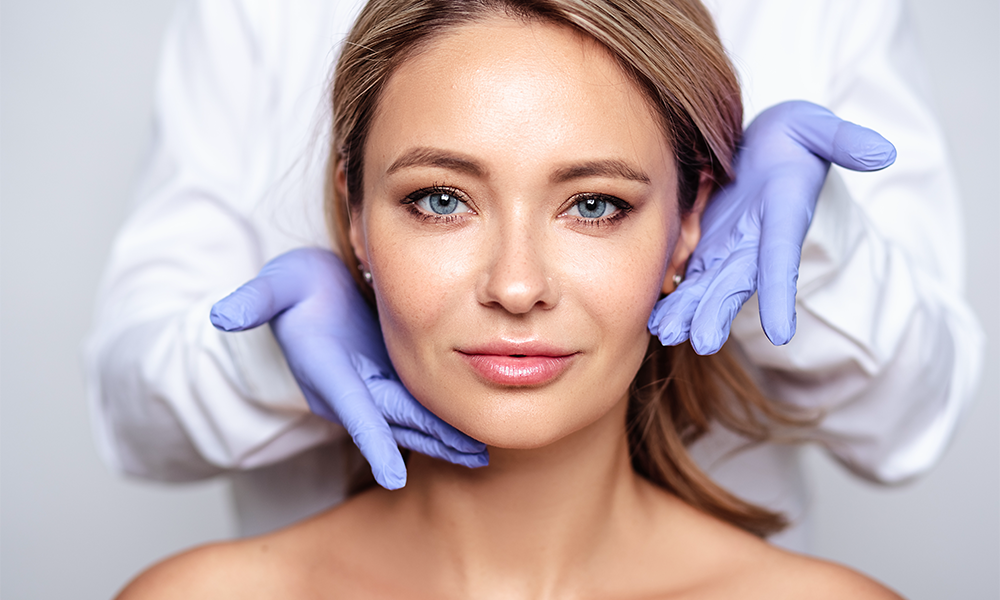 Close up portrait of young blonde woman with aesthetician hands in a gloves