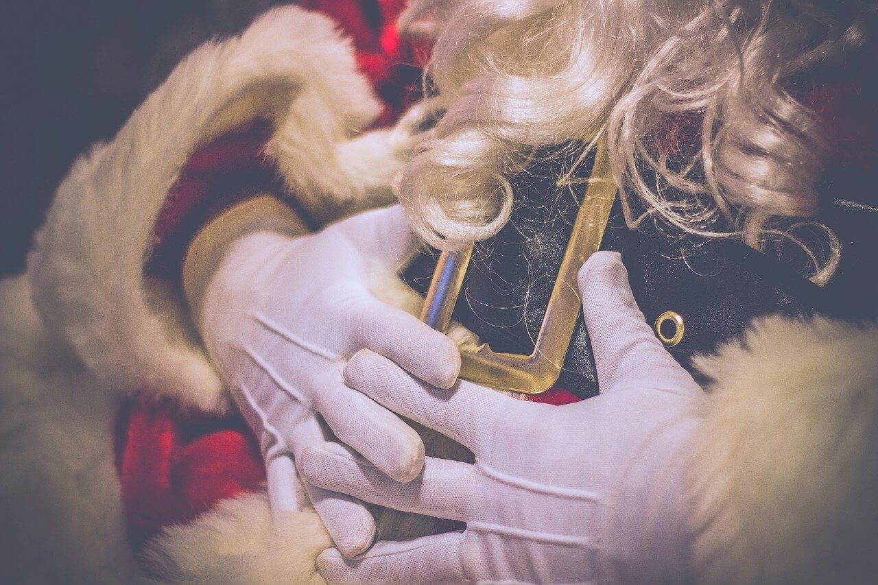 Santa's folded, gloved hands resting on his stomach.