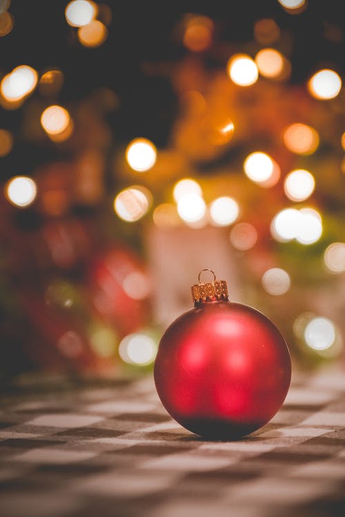 Red ornament with Christmas lights in the background
