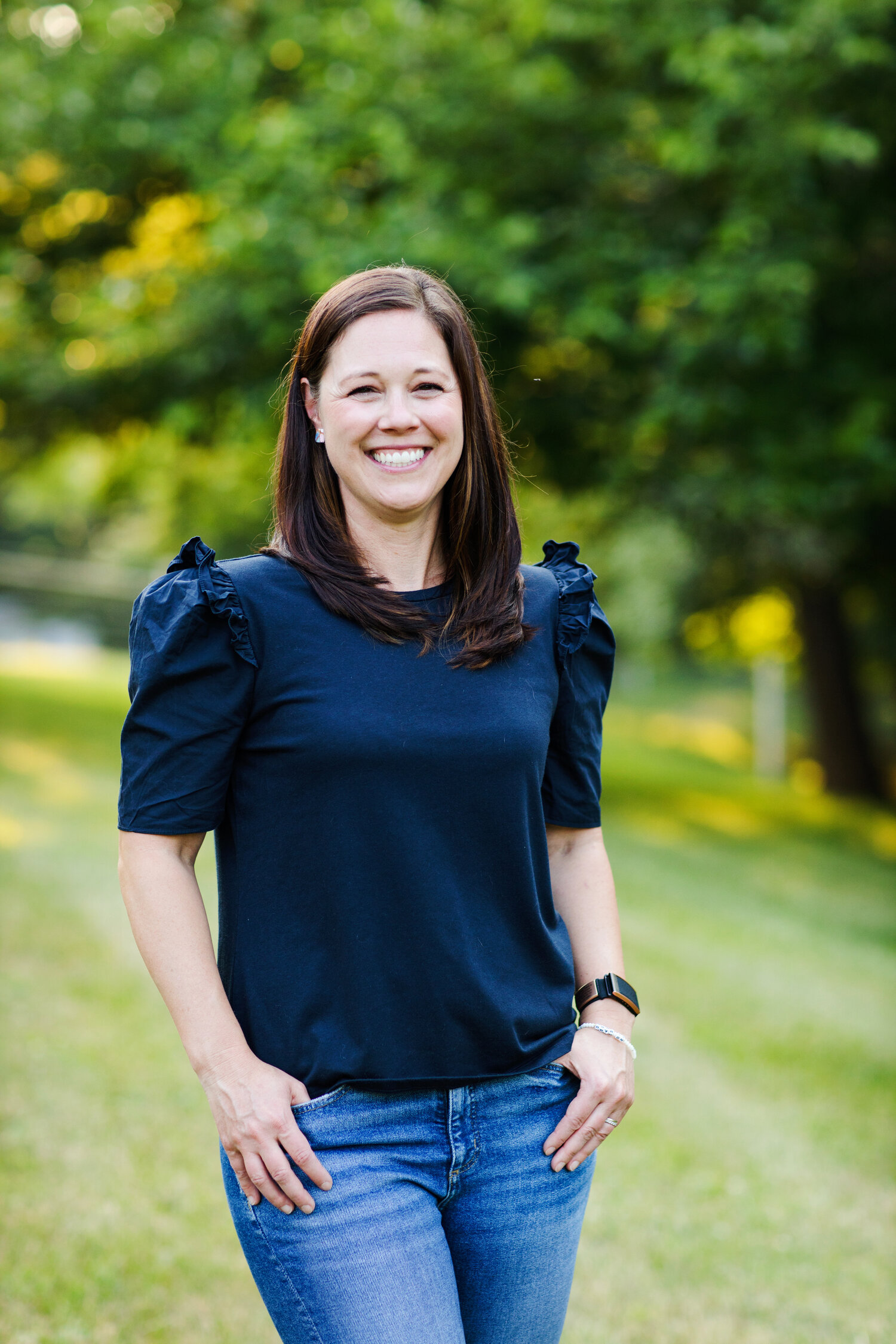 An image of Candice from the Two Alpha Gals. She is wearing a navy blue shirt and is smiling in a grassy field.