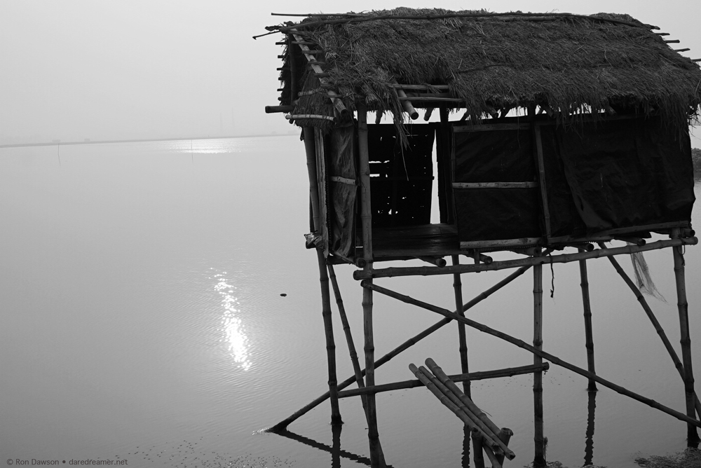 Hut on stilts in water.