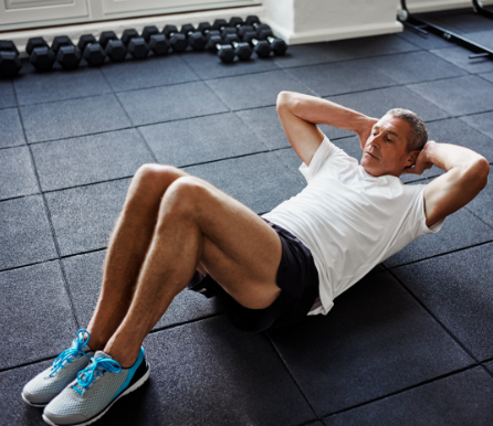 Photo of a man on a gym mat in the middle of a workout, wearing athletic gear and neat blue sneakers.