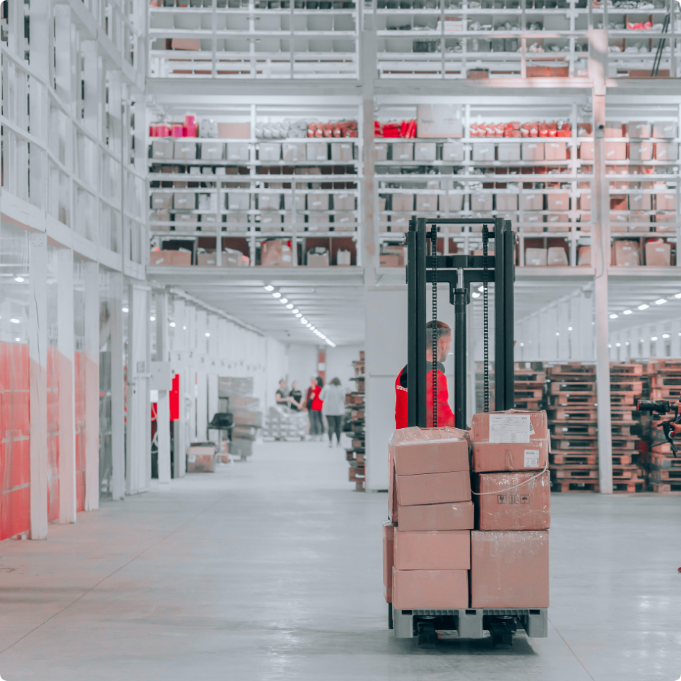 guy driving forklift carrying boxes through warehouse