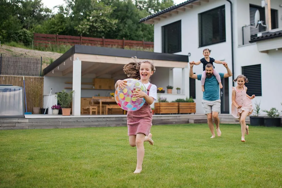Dad with three daughters running and playing in their backyard.
