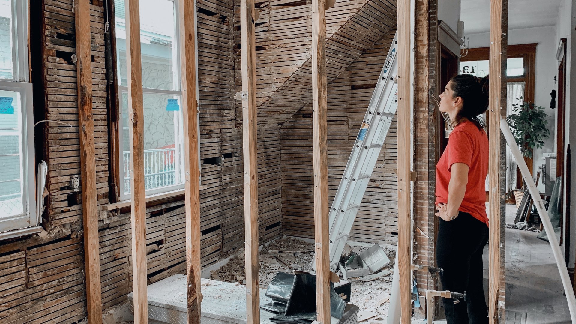 A young woman in a red shirt renovating her home