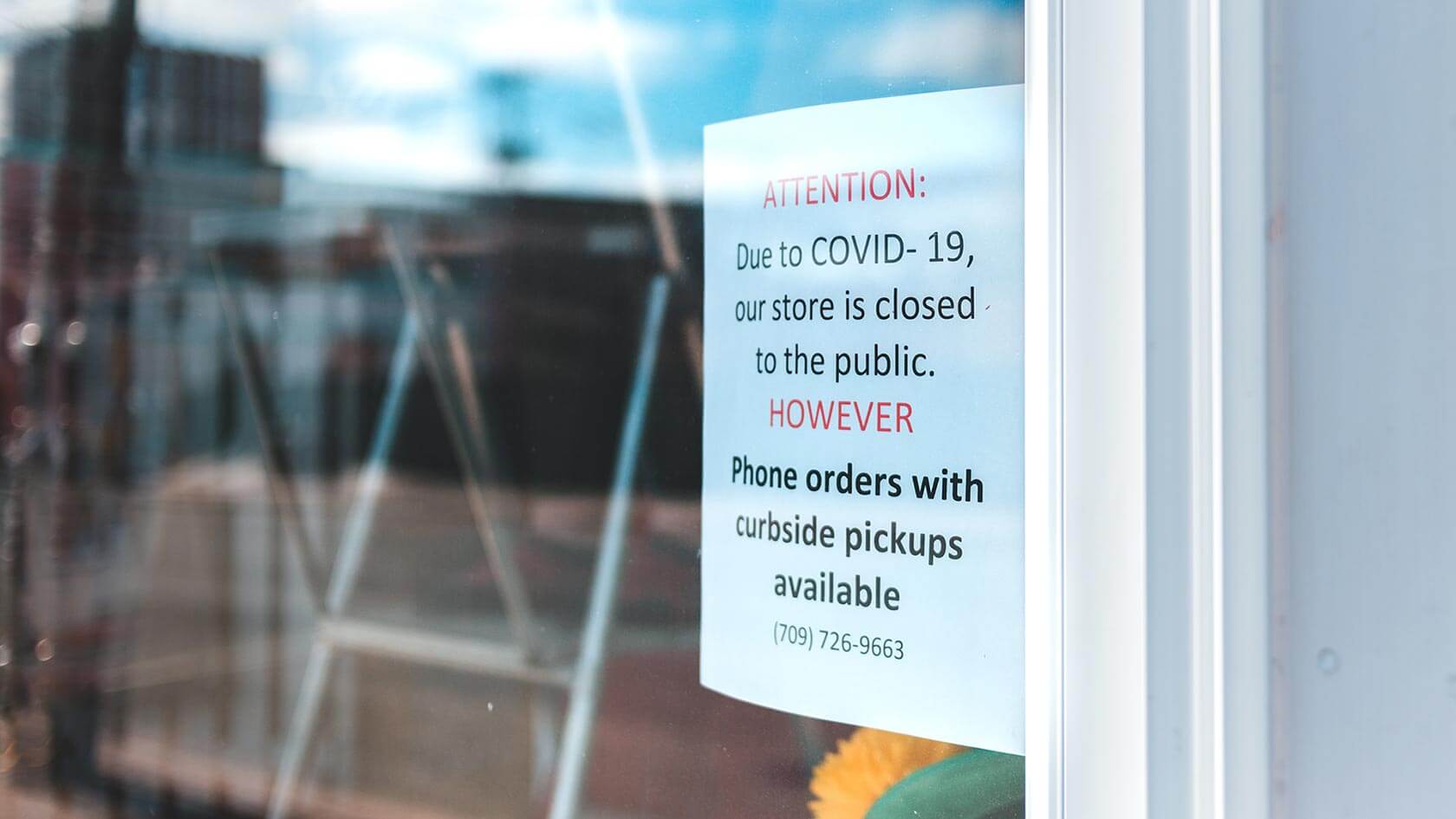 A retail shop front with a sign saying they're closed due to COVID-19