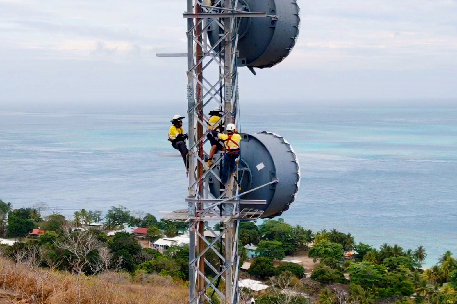 Three people working on an Amplitel tower
