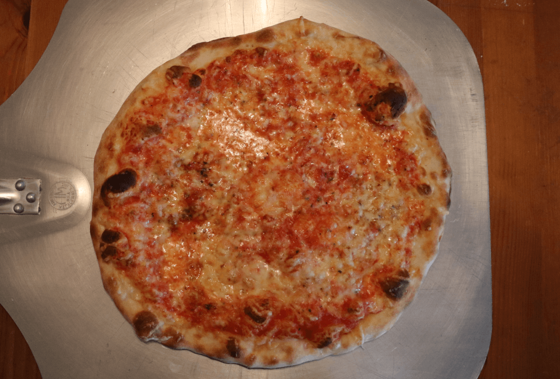 A pizza being sauced