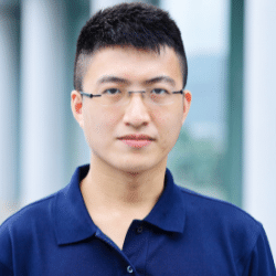 An Asian man wearing a blue polo shirt and glasses