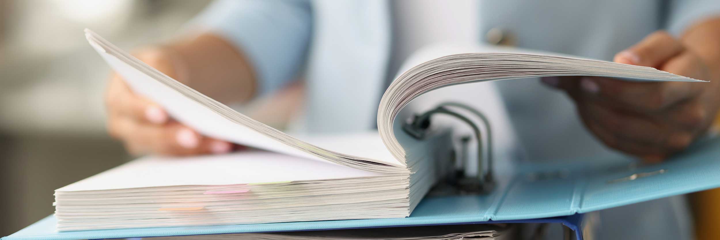 a woman paging through a binder full of regulatory documents