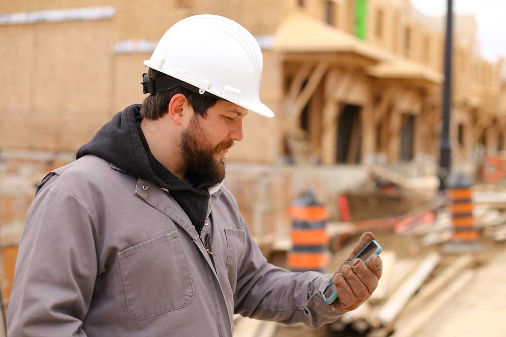 a construction worker capturing data on a phone