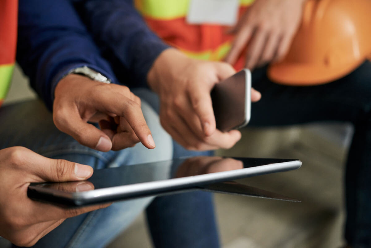 Construction workers share project data with connected construction progress tracking software.