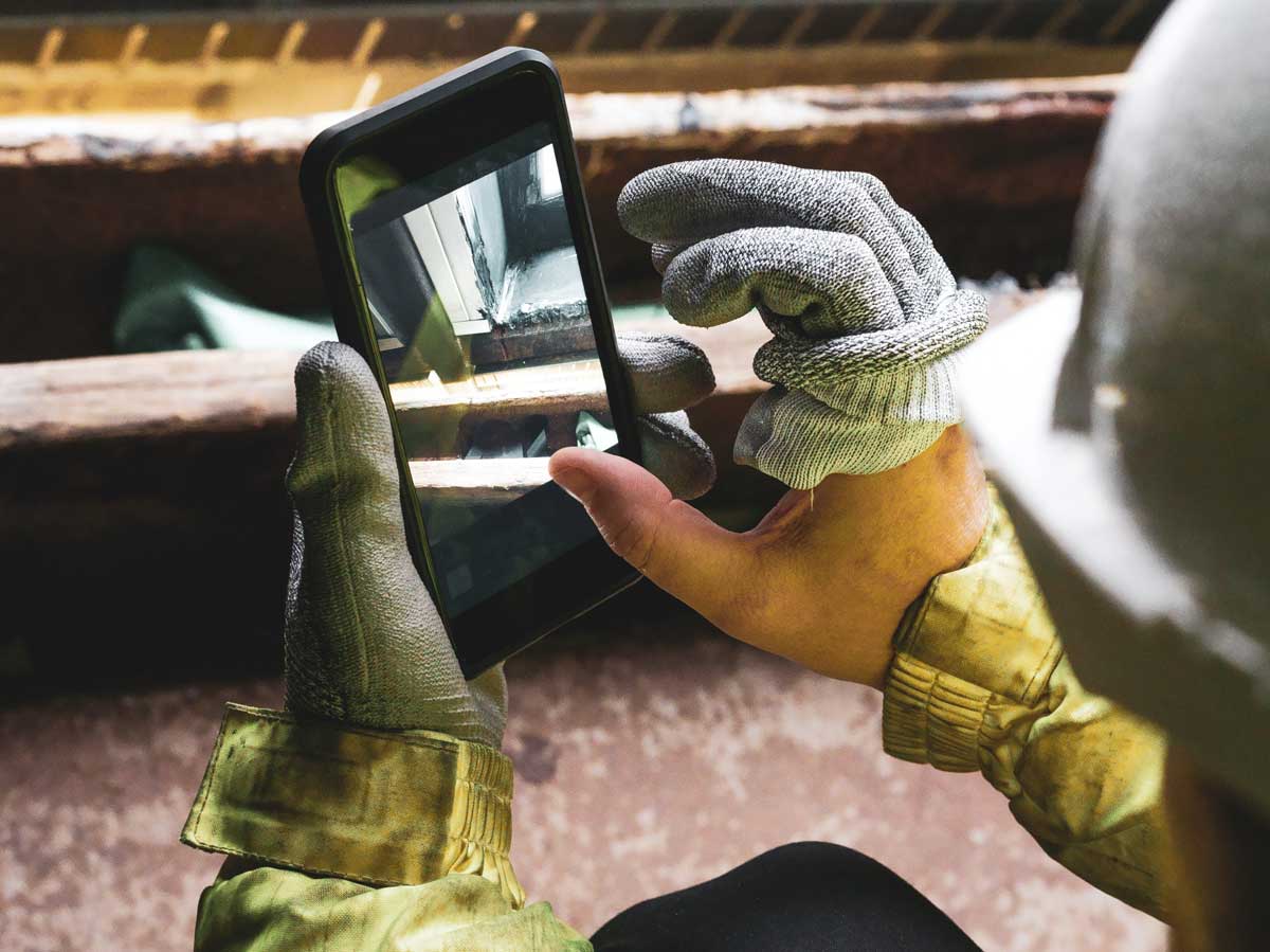 A subcontractor uses his smartphone to take construction progress photos.