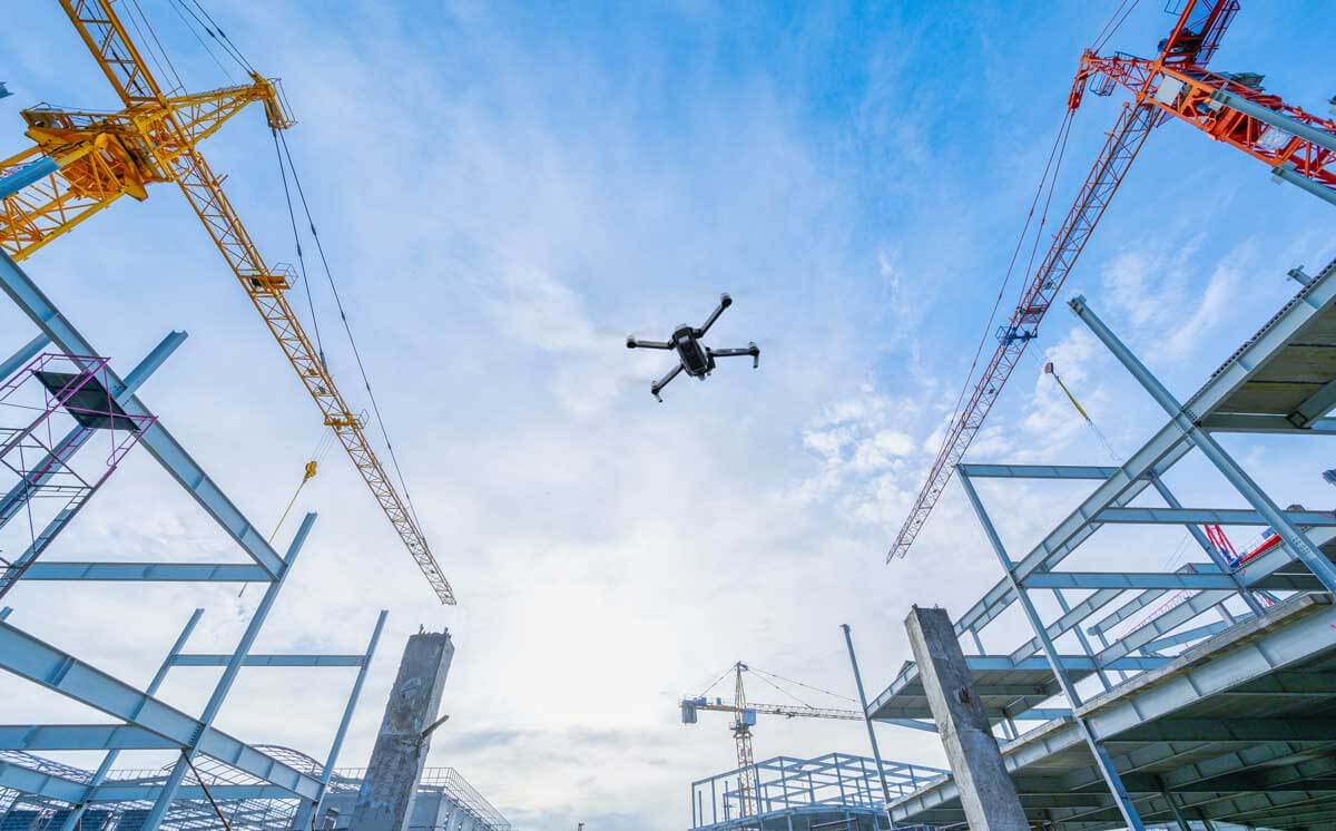 A drone flies over a construction site to capture construction progress photos.