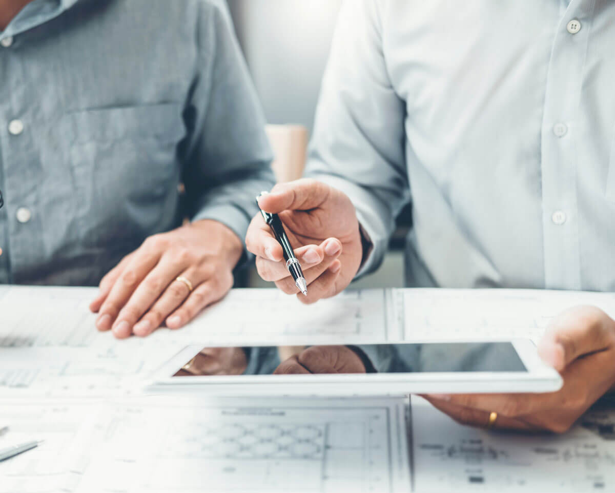 Stakeholders use construction tracking software on a tablet.