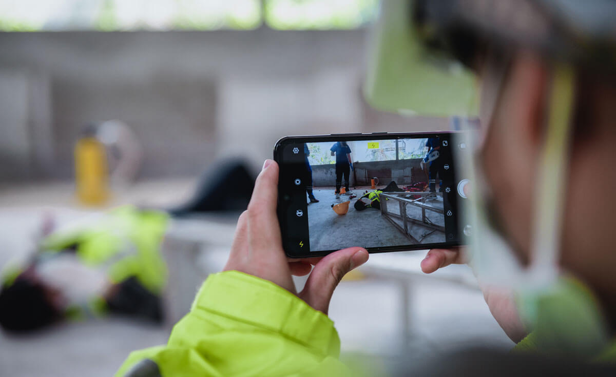 A construction worker documents a jobsite safety incident with photo taken on a smartphone.