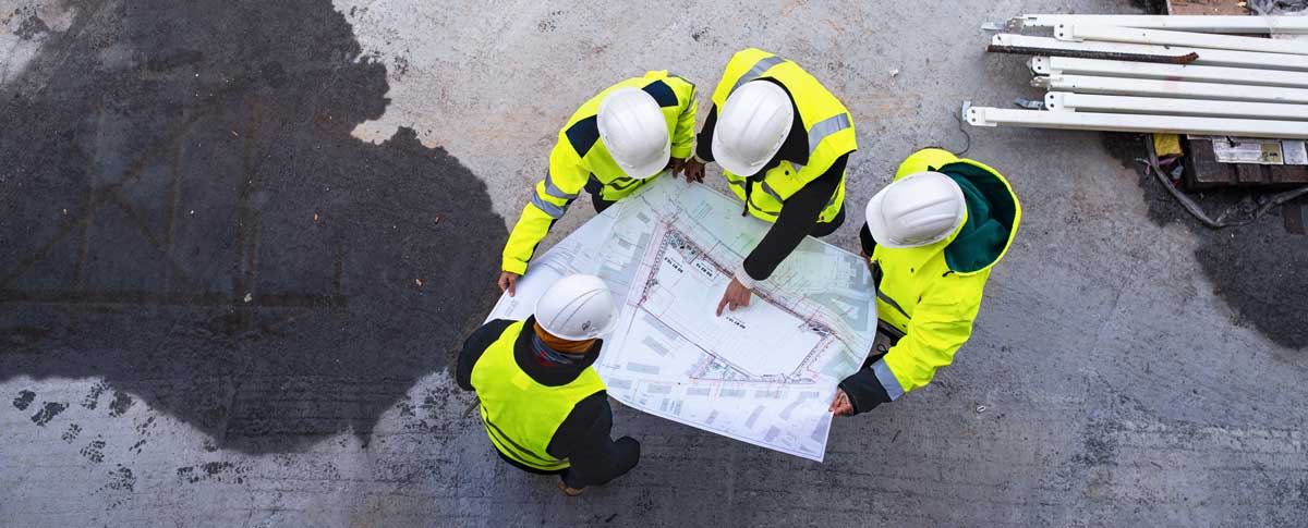 a construction crew examining a paper drawing