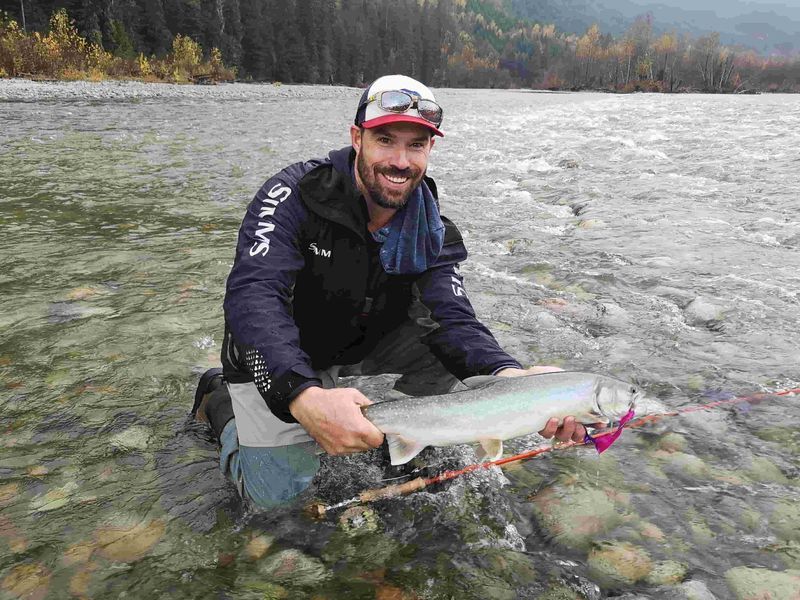 Man crouches in the fraser river to show his catch