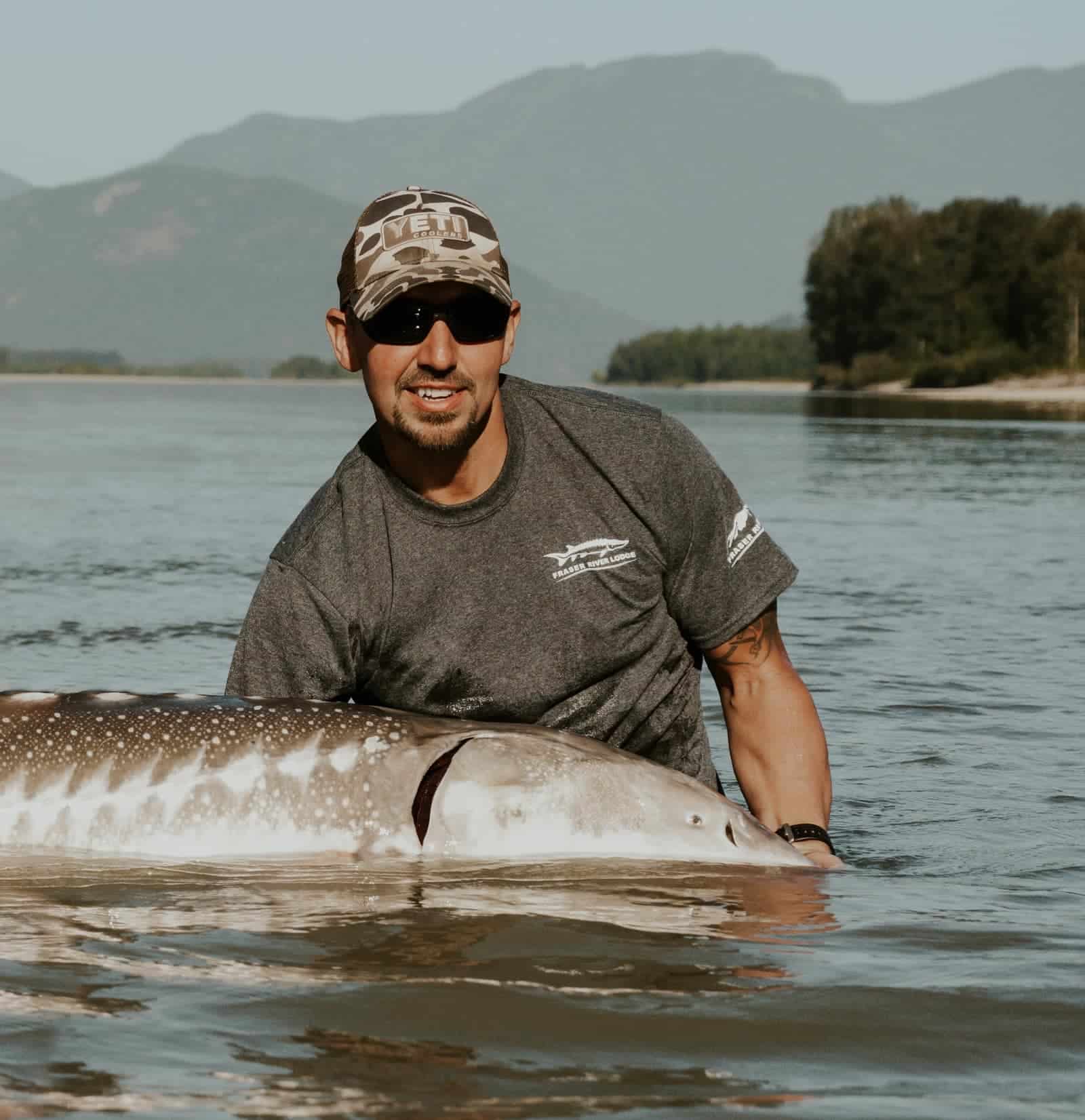 A man holding a sturgeon in the water