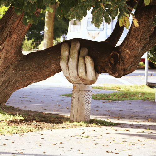 A statue of a hand holding up a tree branch.