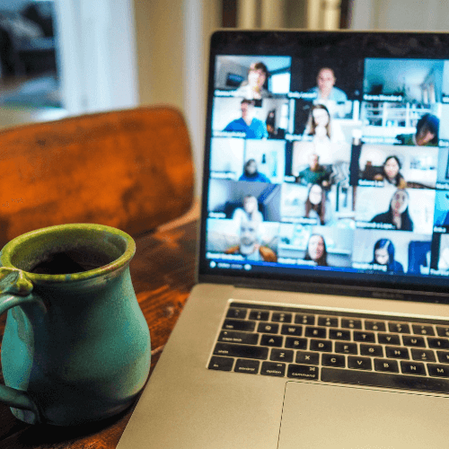 A laptop on a Zoom call with a mug to the left of it.