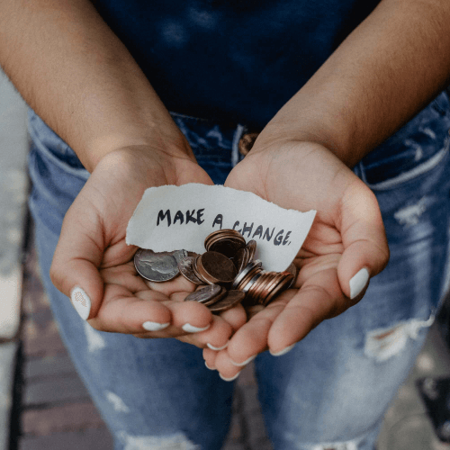 Someone holding their hands out with a collection of coins in their palms.