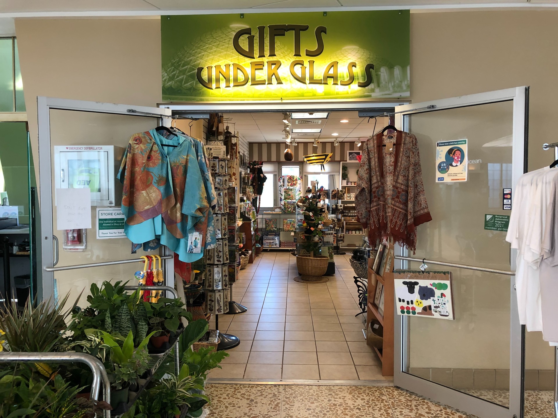 entrance of the gift store with clothes hanging by the entrance and shelves of gifts inside