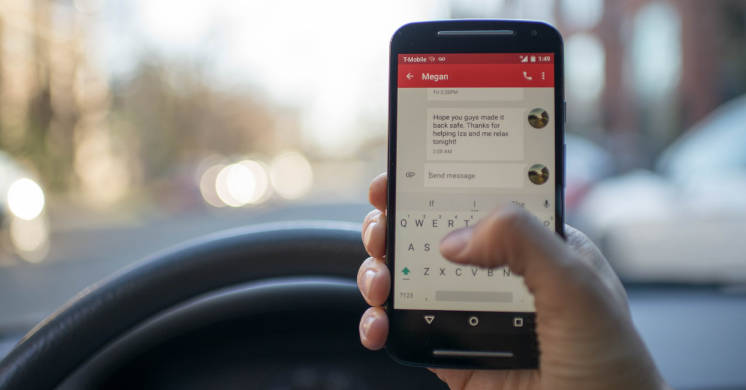 Hand holding cell phone in a car