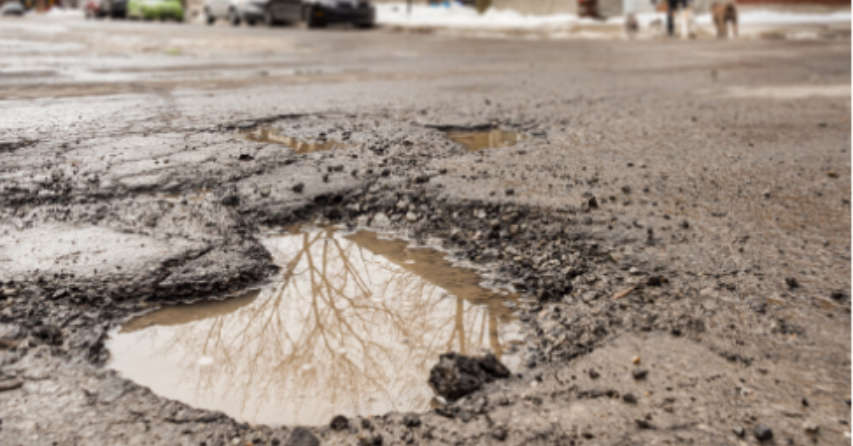 Large pothole filled with water in the middle of the road