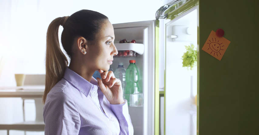 Woman standing in front of open refrigerator
