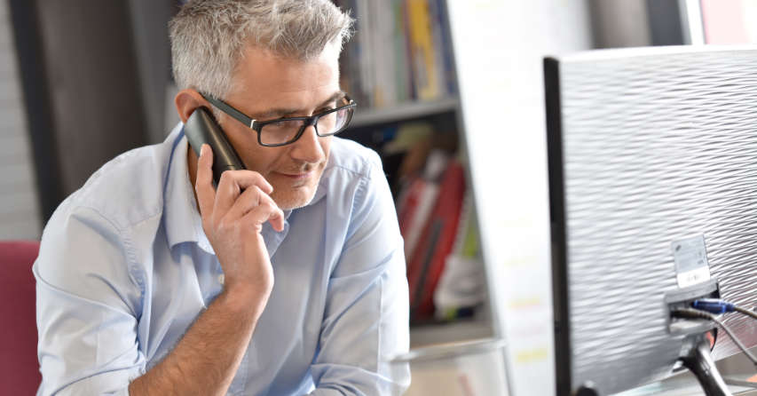Man talking on telephone while looking at a computer screen