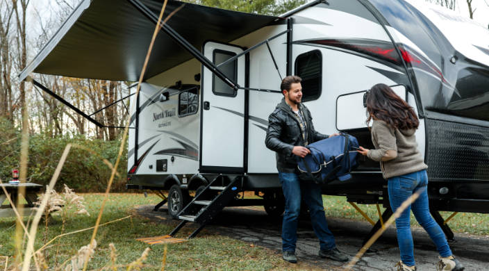man and woman setting up a traile at a campsite