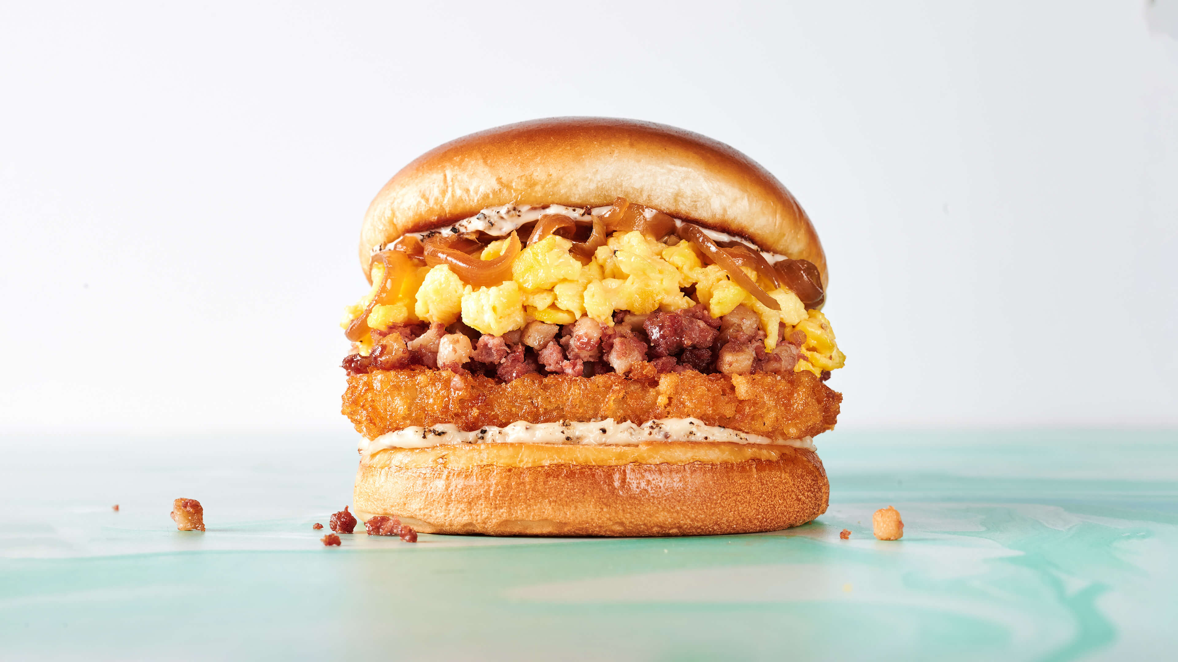 Hangover Helper - Corned beef hash, golden hash brown, egg, caramelized onion, and black pepper aioli on a brioche roll