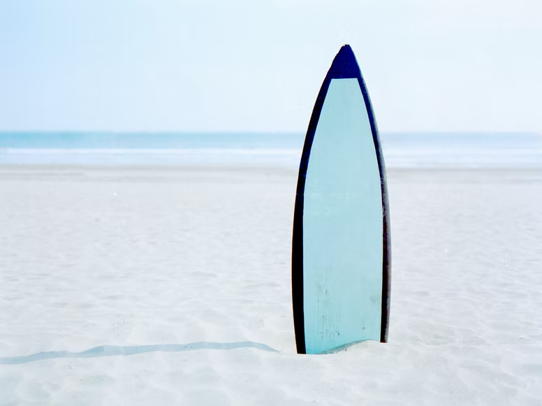 surfboard with a hybrid outline buried half in white sand