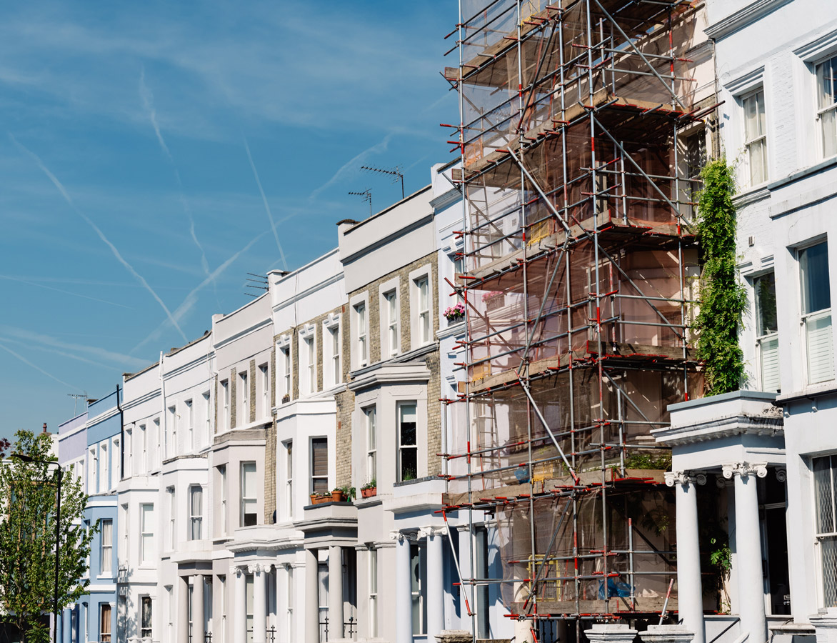 A row of town houses with scaffolding against one of them