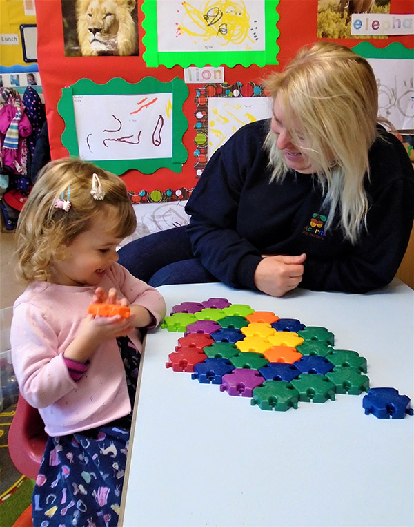 Teach and young girl playing with building blocks