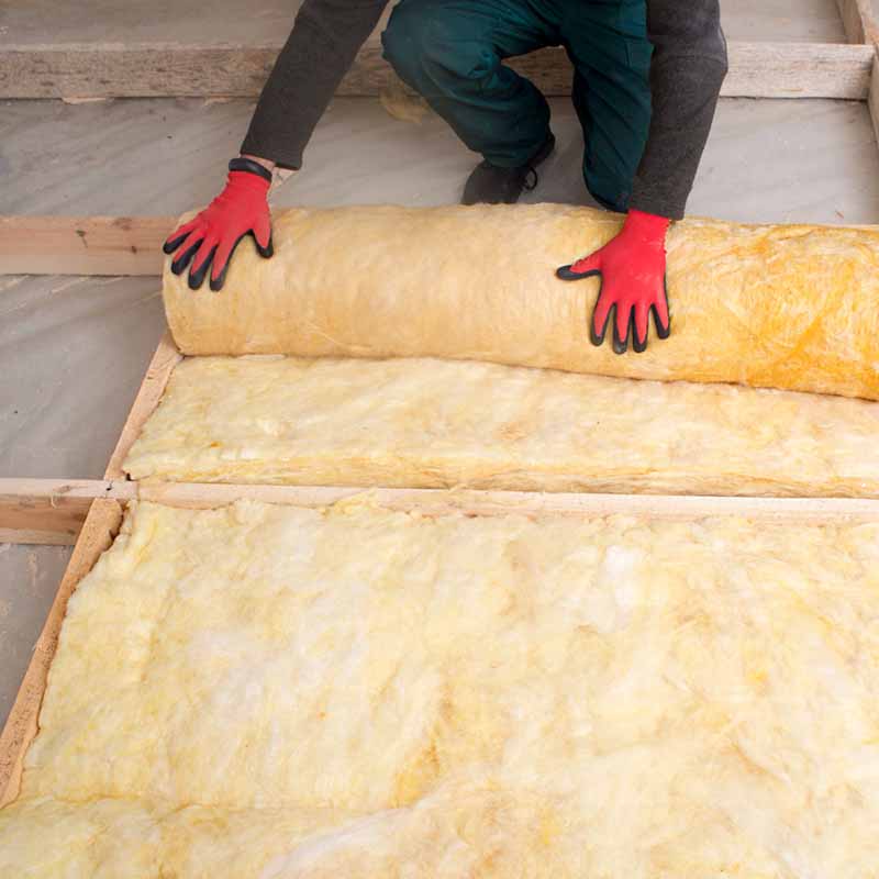 Contractor unrolling fiberglass insulation