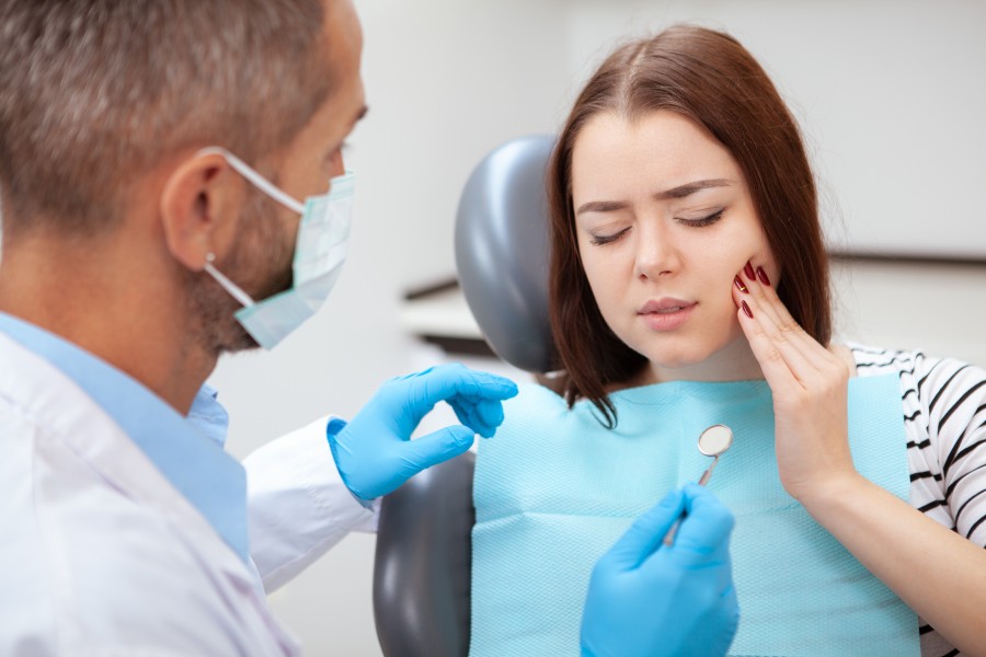 Young woman having toothache, sitting in a dental chair at the clinic