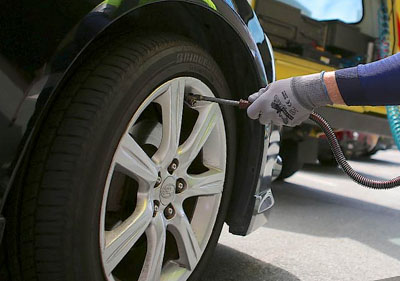 a tow truck operator filling using a hose to pump air into a flat tire