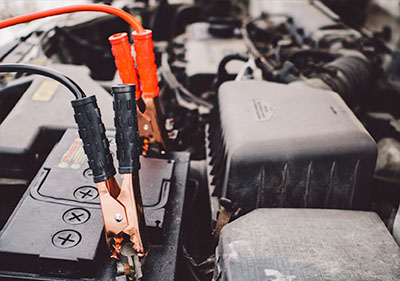 close up of car jumper cables hooked up to a car battery