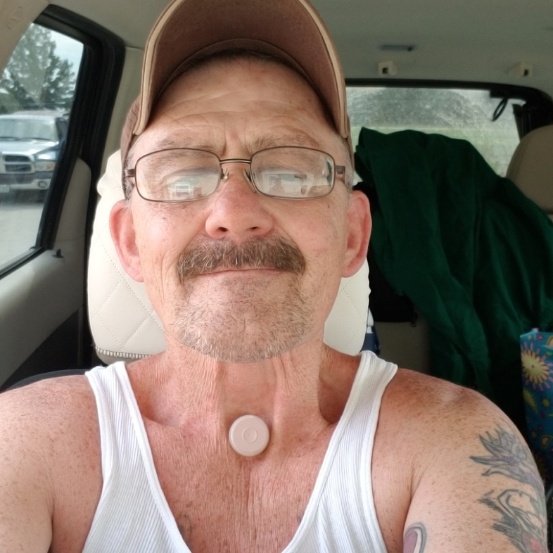 Larry Batt takes a photo of himself seated in the passenger seat of a car. He is smiling slightly.