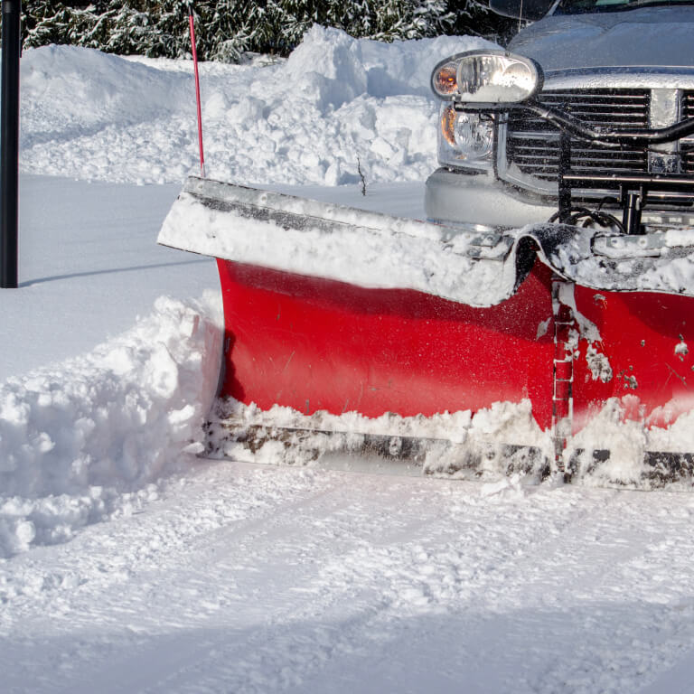 Snow plow driving through the snow for winter commercial property mainentance.